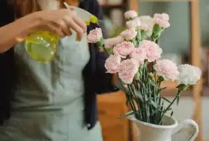 pexels-photo-5409737-5409737 Crop anonymous female florist in apron standing near vase with blooming flowers and spraying water