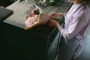 pexels-photo-5894061-5894061 A florist arranges a colorful flower bouquet on a wooden table in a serene indoor setting.